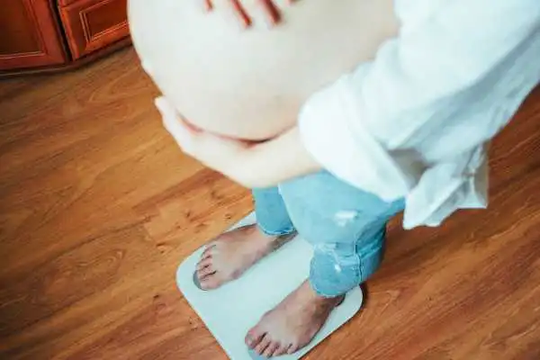 Image of woman weighing herself and experiencing weight gain through pregnancy Dysart